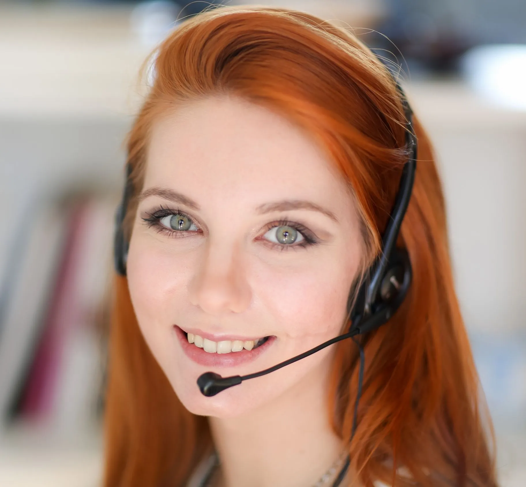 Smiling receptionist wearing a headset in a softly blurred office